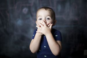 toddler with his hands over his mouth